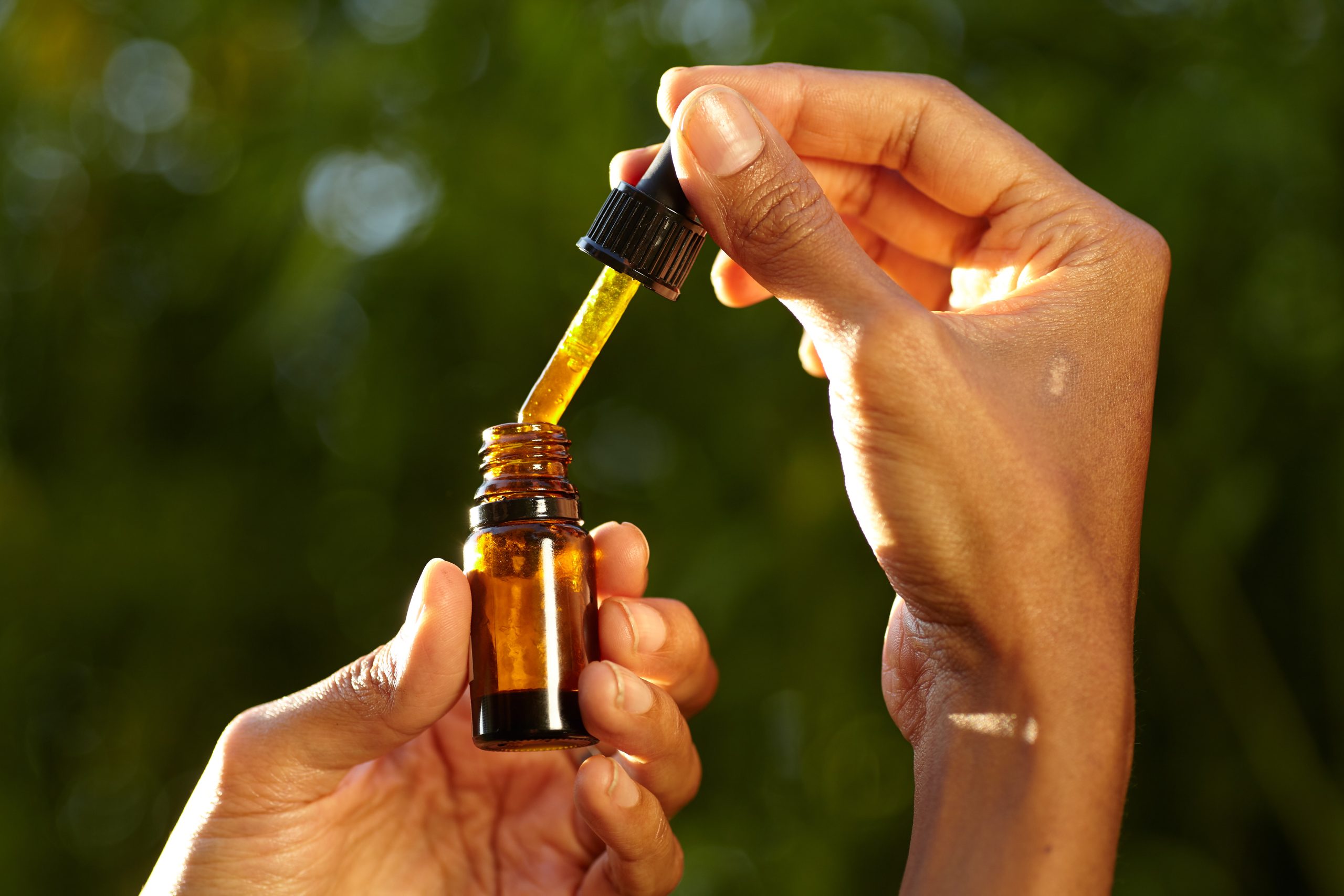 Uma mulher a segurar um conta-gotas com um produto de óleo para ajudar no alívio de dores da Homeopatia