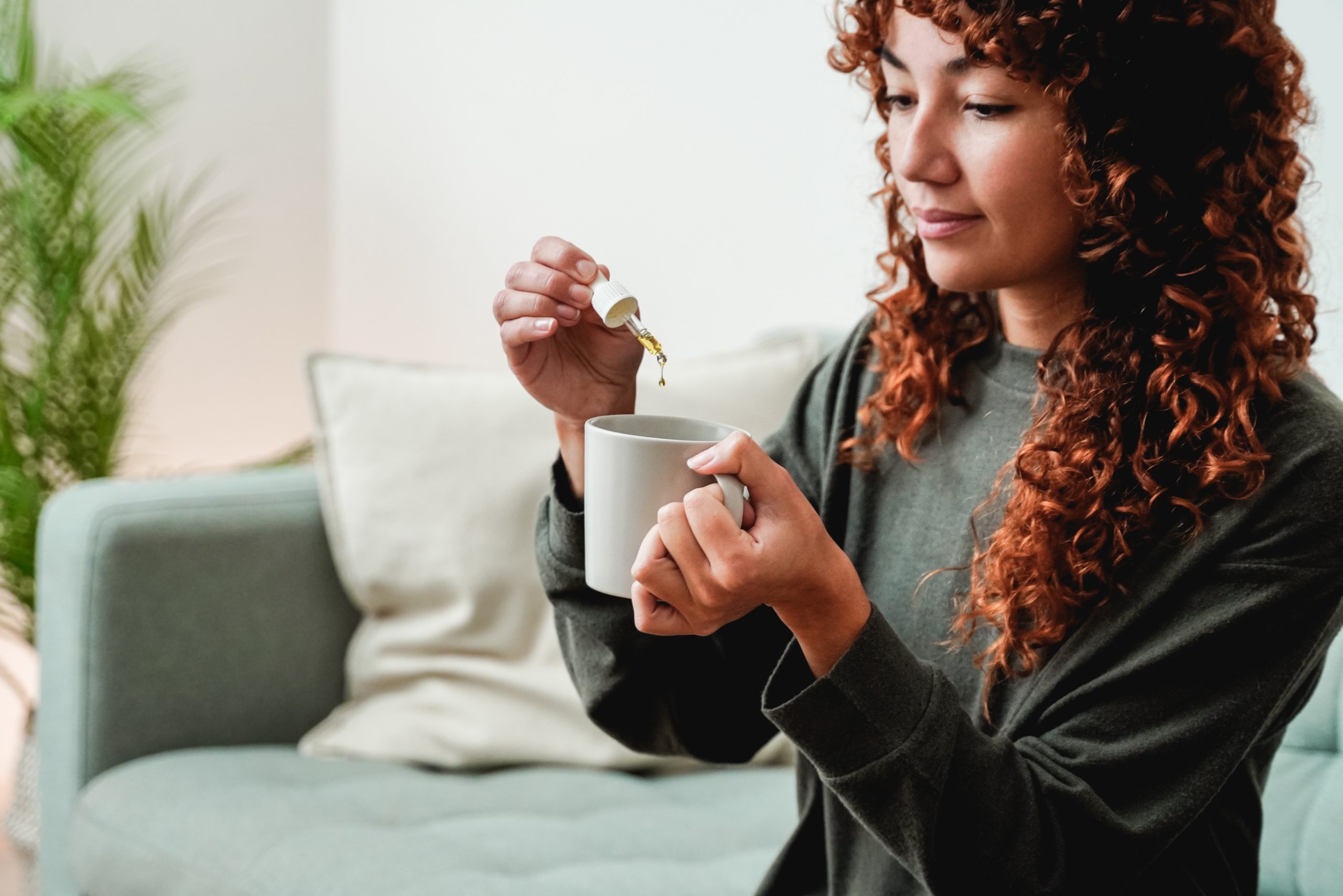 Conta-gotas de óleo Cbd - Mulher jovem a tomar óleo de canábis em chá para tratamento da ansiedade e do stress - Medicina alternativa